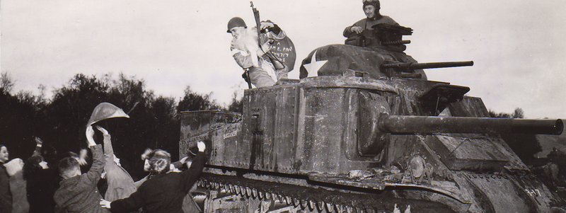 Cover image of Sergeant Hiram Prouty atop a tank dressed as Santa Claus handing candy out to children.