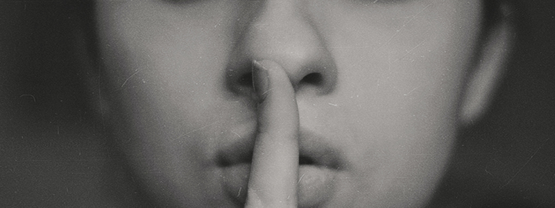 Black and white close-up a woman's mouth as she's hushing with a finger gesture
